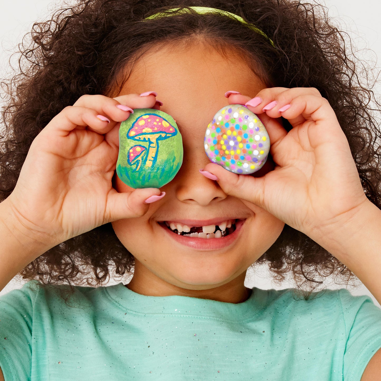 Child displaying colourful finished glow-in-the-dark painted rocks