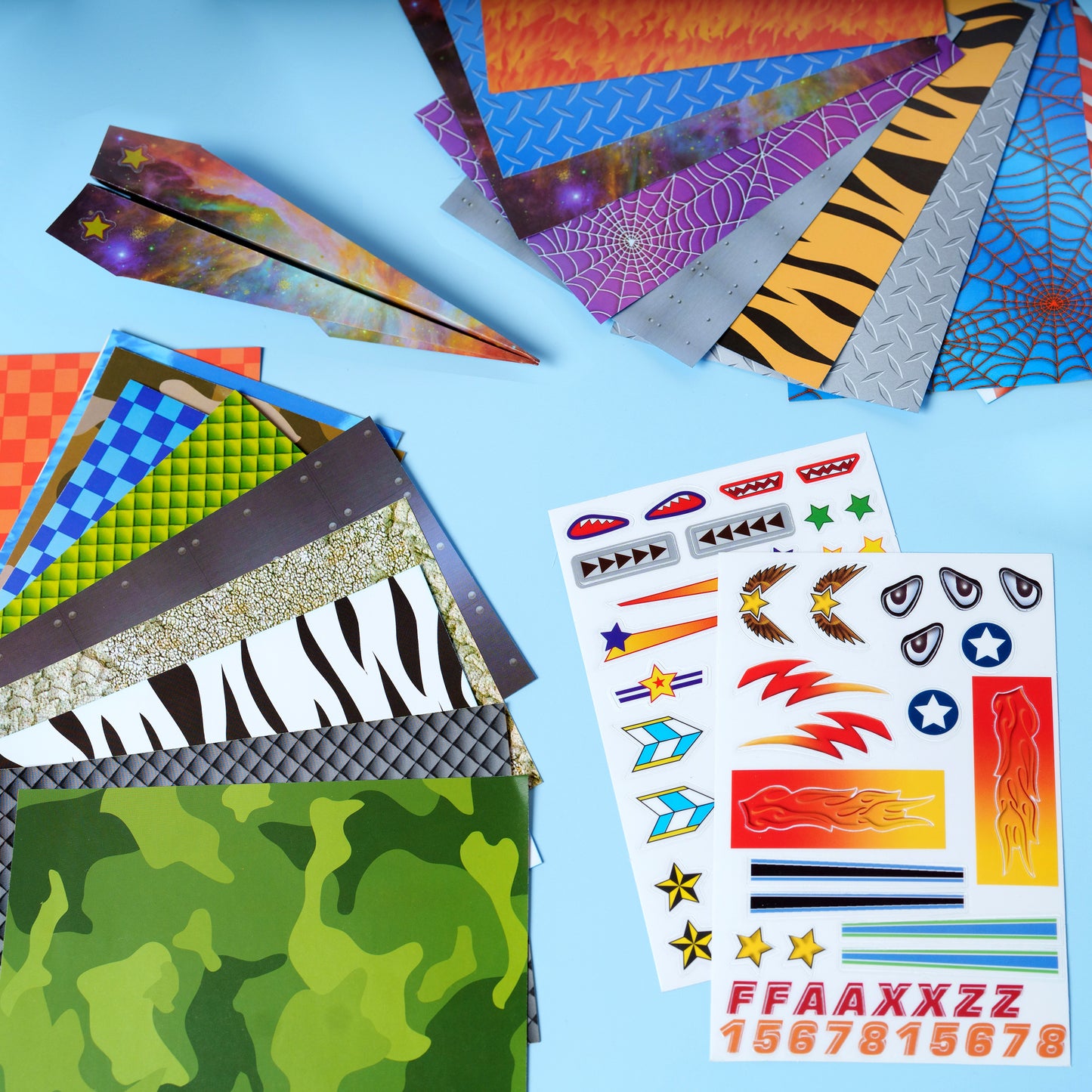 Hands folding and decorating paper airplanes with colourful craft materials