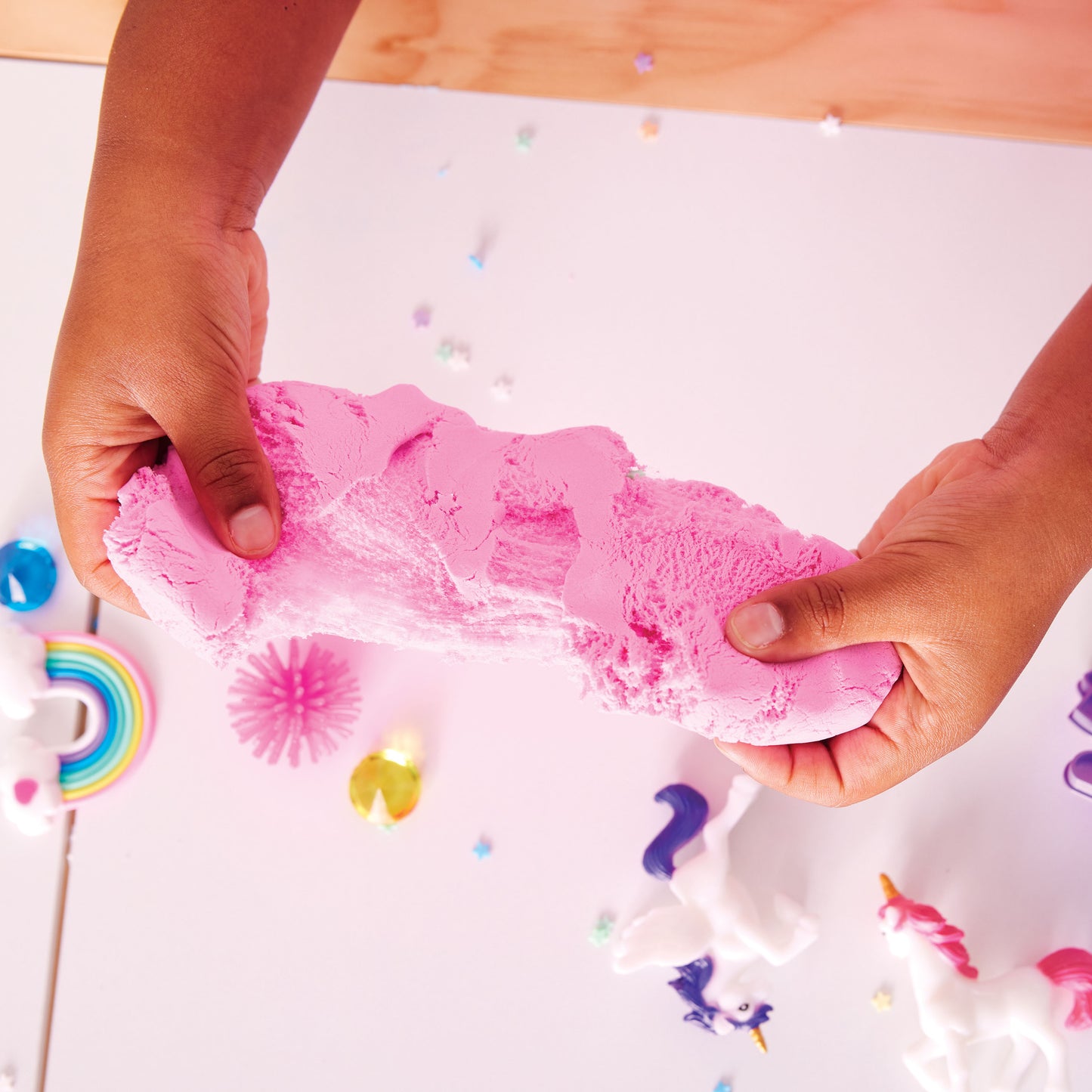 Hands squishing and shaping cloud clay with unicorn sensory accessories