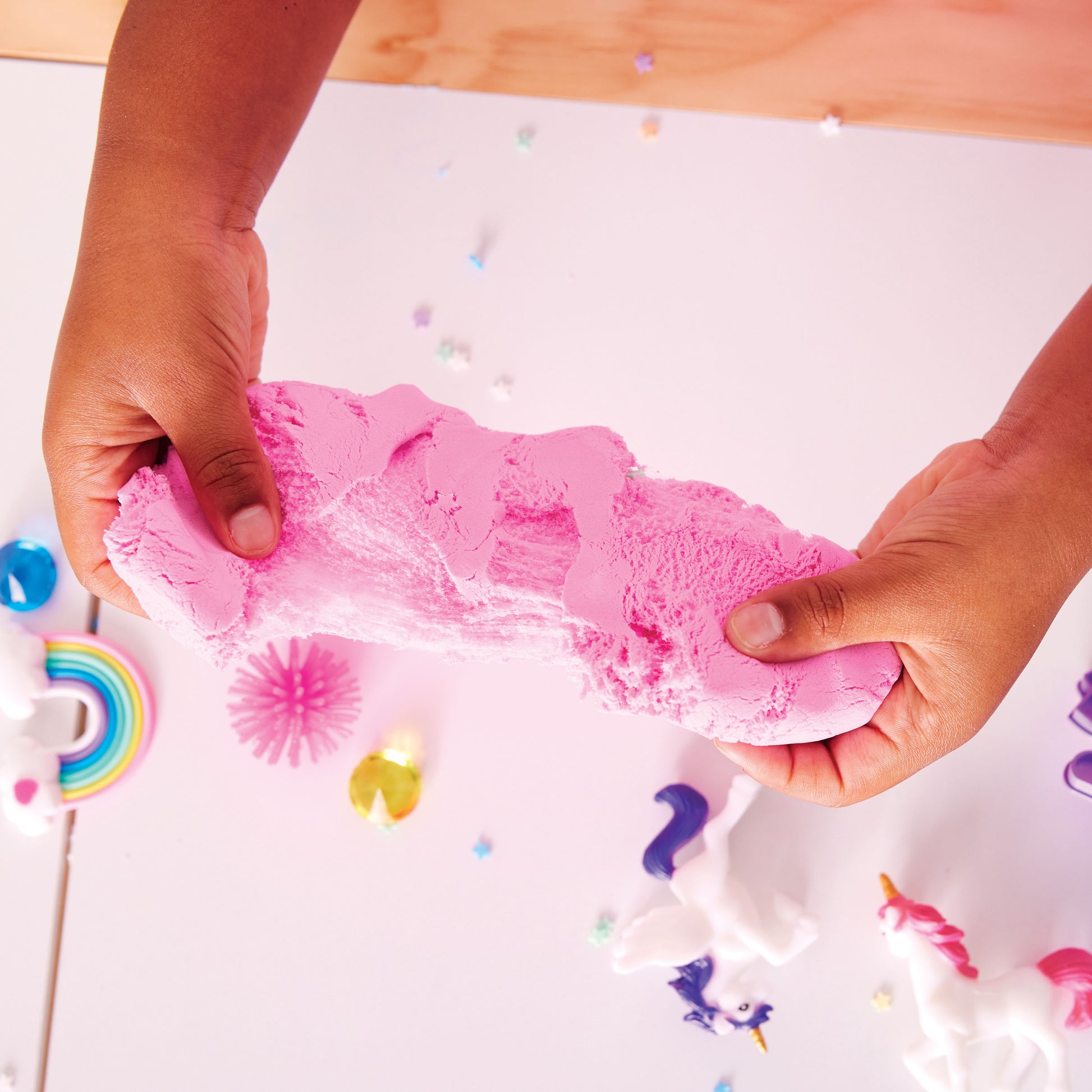 Hands squishing and shaping cloud clay with unicorn sensory accessories